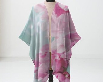 May include: A light blue and pink floral print kimono with a long, flowing design. The kimono is draped over a black stand.