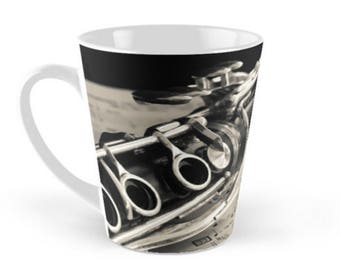 Puede incluir: Una taza de cerámica blanca con una imagen en blanco y negro de un clarinete. El clarinete está enfocado y el fondo está desenfocado.