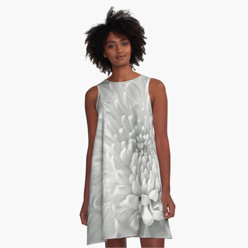 May include: A sleeveless black and white dress with a large, white flower print. The flower is in focus and the background is blurred.