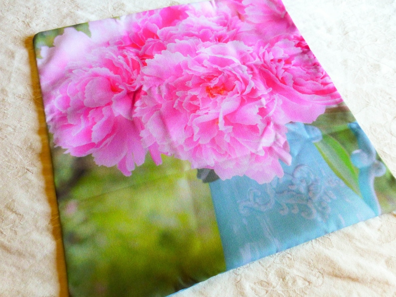 May include: A pink and white floral pillow cover with a blue and white patterned background. The pillow cover features a close-up of pink peonies.