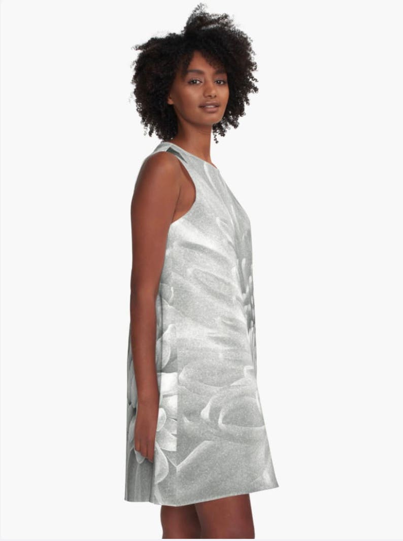 May include: A sleeveless dress with a black and white floral print. The dress has a scoop neck and a loose fit.