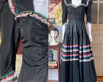 May include: A black vintage gown with a ruffled neckline and sleeves. The skirt features a colorful striped band around the bottom.