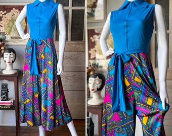 May include: A blue and multi-colored patterned jumpsuit with a blue collared top and a wide blue sash. The jumpsuit has a geometric pattern with paisley accents.