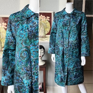 May include: A vintage teal and blue patterned coat with a button-up front and a collar. The coat features a floral and swirl design. The coat is displayed on a mannequin. The coat's length is approximately 40 inches.