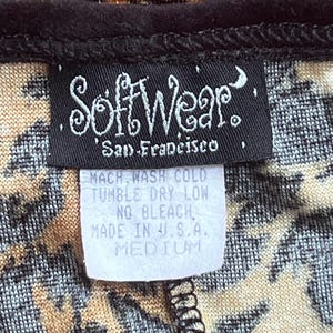 May include: Close-up of a garment with a leopard print pattern. A black label reads "SoftWear, San Francisco." A smaller tag indicates care instructions: "MACH WASH COLD, TUMBLE DRY LOW, NO BLEACH, MADE IN U.S.A., MEDIUM."