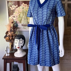 May include: A blue and white short-sleeved dress with a turtle print and a blue sash tie.