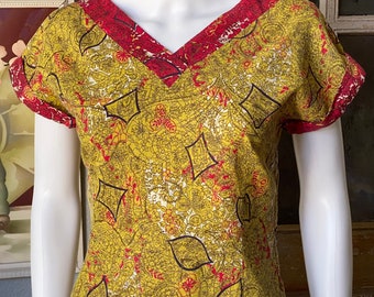 Pode incluir: Uma blusa amarela e vermelha com padrão e mangas curtas, com decote em V.