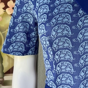 May include: A blue and white short-sleeved dress with a turtle pattern. The dress has a blue collar and a blue waistband.