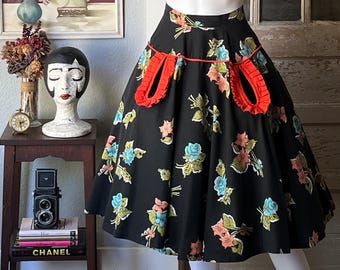 May include: A black and white floral print skirt with red ruched details. The skirt has a full circle shape and a high waist.