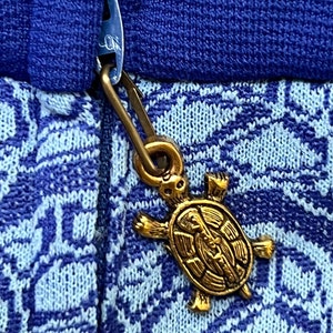 May include: A blue and white patterned jumper with a gold turtle zipper pull.
