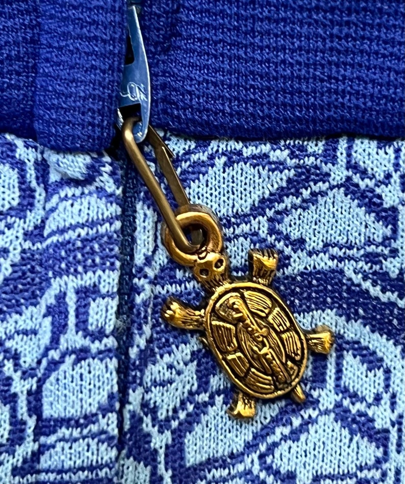 May include: A blue and white patterned jumper with a gold turtle zipper pull.