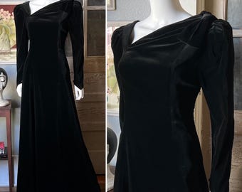 May include: A long black velvet dress with a cowl neck and puff sleeves.