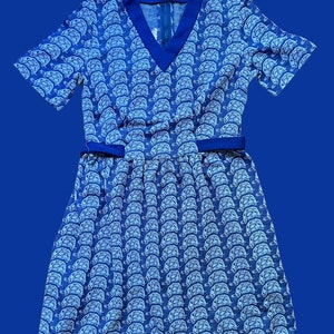 May include: A blue and white short-sleeved dress with a v-neck and a pattern of white turtles on a blue background.