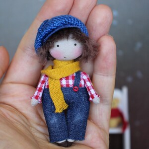 Junge Puppe in Jeans, blauer Mütze und rotem Schal