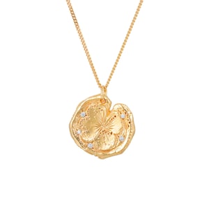 May include: A gold necklace with a large, round pendant. The pendant is textured and has a starburst design with four small diamonds set in the center. The necklace is on a white background.