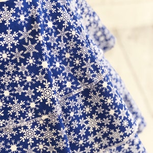 May include: A blue fabric with a white snowflake pattern. The fabric is folded over itself, creating a layered effect.