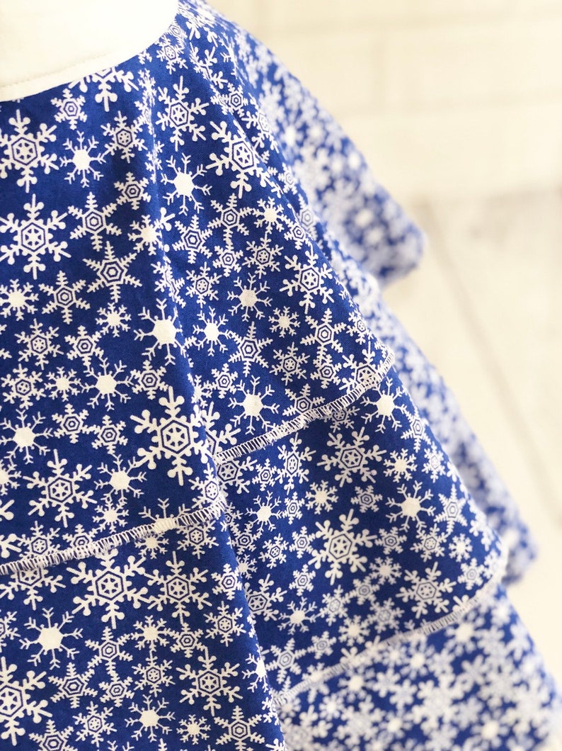 May include: A blue fabric with a white snowflake pattern. The fabric is folded over itself, creating a layered effect.