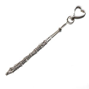 May include: A silver-toned keychain with a heart-shaped clasp. The chain features a decorative, openwork design with a series of interconnected, geometric shapes. The keychain is designed to attach to keys or other small items.