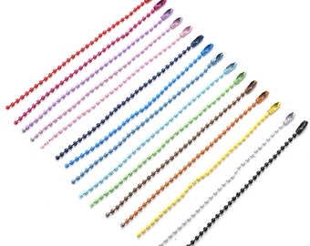 Pode incluir: Uma variedade de colares de corrente de bolinhas coloridas em vários tons, incluindo vermelho, roxo, azul, verde e amarelo. Cada corrente tem um fecho correspondente na parte superior e um design de corrente de bolinhas. As correntes são dispostas diagonalmente sobre um fundo branco.