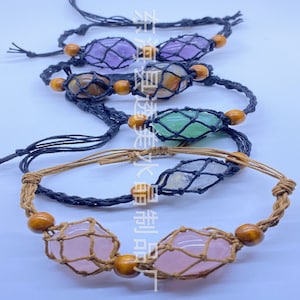 Op de afbeelding: Een set van vijf armbanden met verschillende gekleurde stenen, elke steen is ingekapseld in een macramé-net. De armbanden zijn gemaakt van bruin en zwart touw en hebben houten kralen.