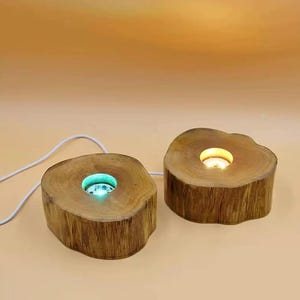 May include: Two wooden lamp bases with a circular cutout in the top. The base on the left has a green light shining through the cutout, while the base on the right has a yellow light shining through the cutout.