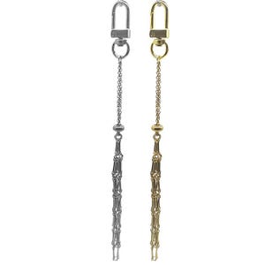 May include: Two metal keychains, one silver and one gold, each with a clasp, chain, and decorative bamboo-like charm. The silver keychain is on the left, and the gold keychain is on the right. The charms are approximately 4 inches long.