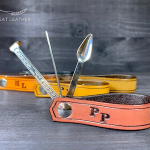 May include: A brown leather pipe tool with a silver metal tamper, poker, and a small scoop. The tool is personalised with the initials "PP".