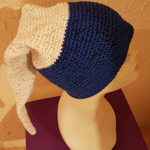 Peut inclure: Un bonnet crocheté blanc et bleu avec une longue queue pointue. Le bonnet est sur une tête de mannequin.