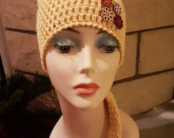 Un bonnet de lutin jaune pâle en pure laine et ses boutons fleurs de bois, crocheté en brides