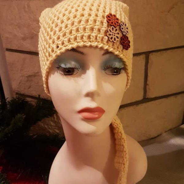 Un bonnet de lutin jaune pâle en pure laine et ses boutons fleurs de bois, crocheté en brides