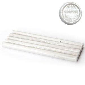 May include: A collection of white wax sticks and a circular wax seal with the text "WAX SAMPLE IMPRESSION". The wax sticks are cylindrical and appear to be made of a pearlescent material. The seal is also white and has a raised design.