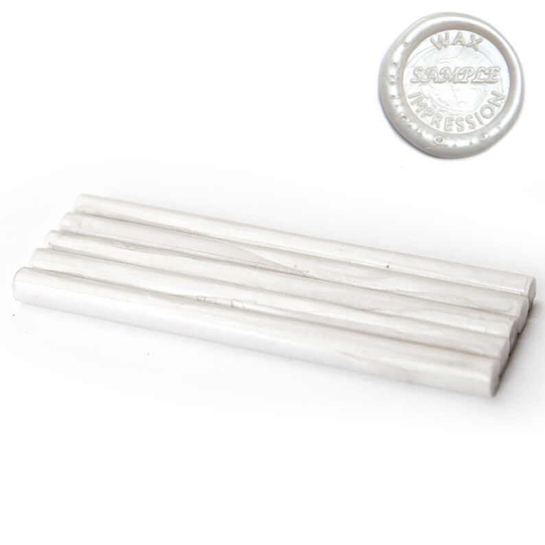 May include: A collection of white wax sticks and a circular wax seal with the text "WAX SAMPLE IMPRESSION". The wax sticks are cylindrical and appear to be made of a pearlescent material. The seal is also white and has a raised design.