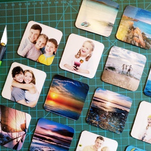 May include: A collection of square photo tiles featuring a variety of images, including family portraits, landscapes, and seascapes. The tiles are arranged on a green cutting mat.