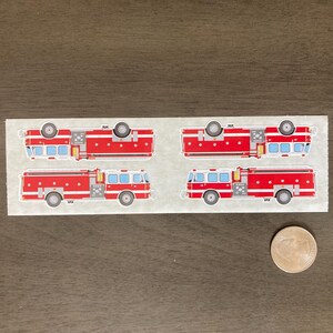 May include: A sheet of stickers featuring four red fire trucks with white and blue details. Two trucks are oriented upright, and two are upside down. A quarter coin is next to the stickers for size comparison.