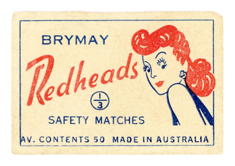 May include: A vintage matchbox with a red and blue design. The box features a cartoon illustration of a woman with red hair and the text "Brymay Redheads Safety Matches Av. Contents 50 Made in Australia".