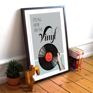以下が含まれることがあります： グレーの背景に黒い文字で「It's all here on the Vinyl」と書かれた黒い額縁付きのプリント。プリントの右下隅には、赤いラベルの黒いビニールレコードが一部見えている。