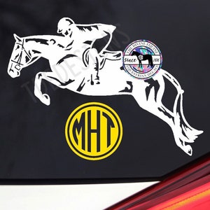 May include: White silhouette of a horse jumping over a fence with a rider on its back. The horse is facing the left side of the image. Below the horse is a yellow circle with a black monogram "MHT" inside. The image also includes a small, colorful logo with the text "The Divine Equine since 2016 Equestrian Decals".