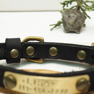 K&ouml;nnte beinhalten: Schwarzes Lederhundekragen mit einer Messing-Schnalle und einem Messing-Namensschild mit der Gravur "Leo".