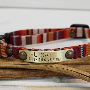 Könnte beinhalten: Ein rot-weiß-braunes gestreiftes Hundehalsband mit einem Messinganhänger, auf dem "*LISA* 213-456-7890" steht.