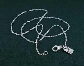 Puede incluir: Un collar de cadena de plata con una pequeña etiqueta de plata que dice "R.W. Miriam".