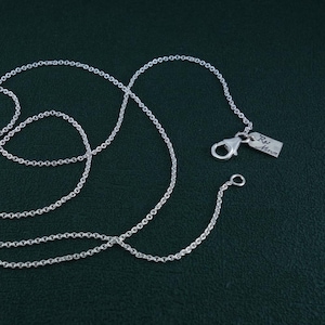Peut inclure: Un collier en chaîne argent avec une petite étiquette en argent qui dit "RJ Marum".