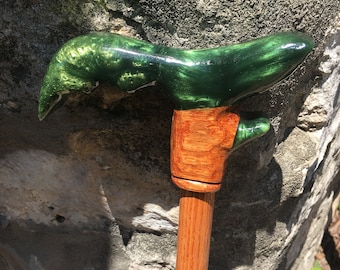 May include: A walking stick with a green and gold resin handle and a wooden shaft with a colorful geometric design.