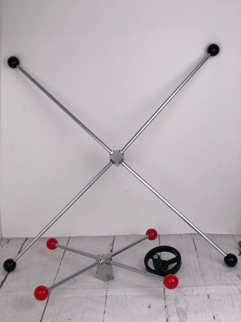 May include: Two silver metal structures with black and red spheres. One structure is a cross shape with black spheres at the ends. The other is a star shape with red spheres. A black wheel is also present.
