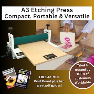 May include: A3 etching press with a green roller and a light wood base. The image shows the press in use, with a print being lifted. The text reads "Compact, Portable & Versatile" and "Tried & trusted by 100's of customers Worldwide."