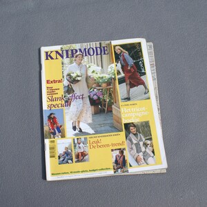 May include: A fashion magazine titled "KNIPMODE" with a yellow and white cover. The cover features images of women in various outfits, with text including "Extra!" and "Slank effect special."