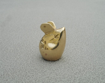 May include: A small, gold-colored mouse figurine with large ears and a rounded body. The mouse is made of a shiny, reflective material and sits upright. The figurine is a decorative item.