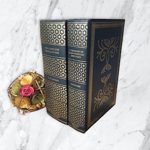 May include: Two hardcover books with gold-embossed designs on the covers. The book on the left is titled "The Complete Works of Saki" by H.H. Munro. The book on the right is titled "A Treasury of Hans Christian Andersen" by Haugaard.