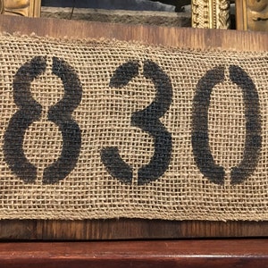 May include: A rustic wooden sign with the number 18301 printed on a hessian background. The sign is secured with metal tacks.