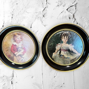 Puede incluir: Dos retratos enmarcados de niñas jóvenes en marcos de estilo vintage. Los marcos son negros con detalles dorados. Los retratos son de estilo pictórico.