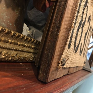 May include: A rustic wooden sign with the word "Welcome" printed on burlap fabric. The sign is attached to a wooden frame and has a distressed look.